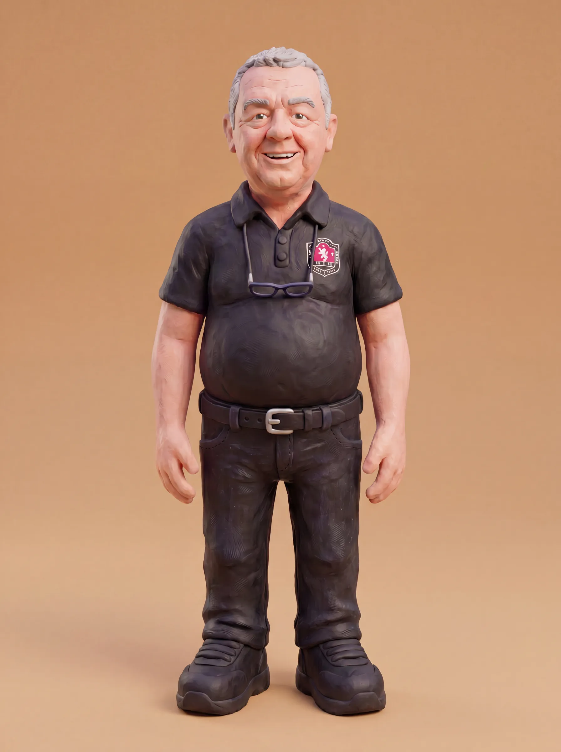 Clay model of Dean standing tall and smiling, in a black polo shirt with the crest on the chest and his reading glasses on a cord